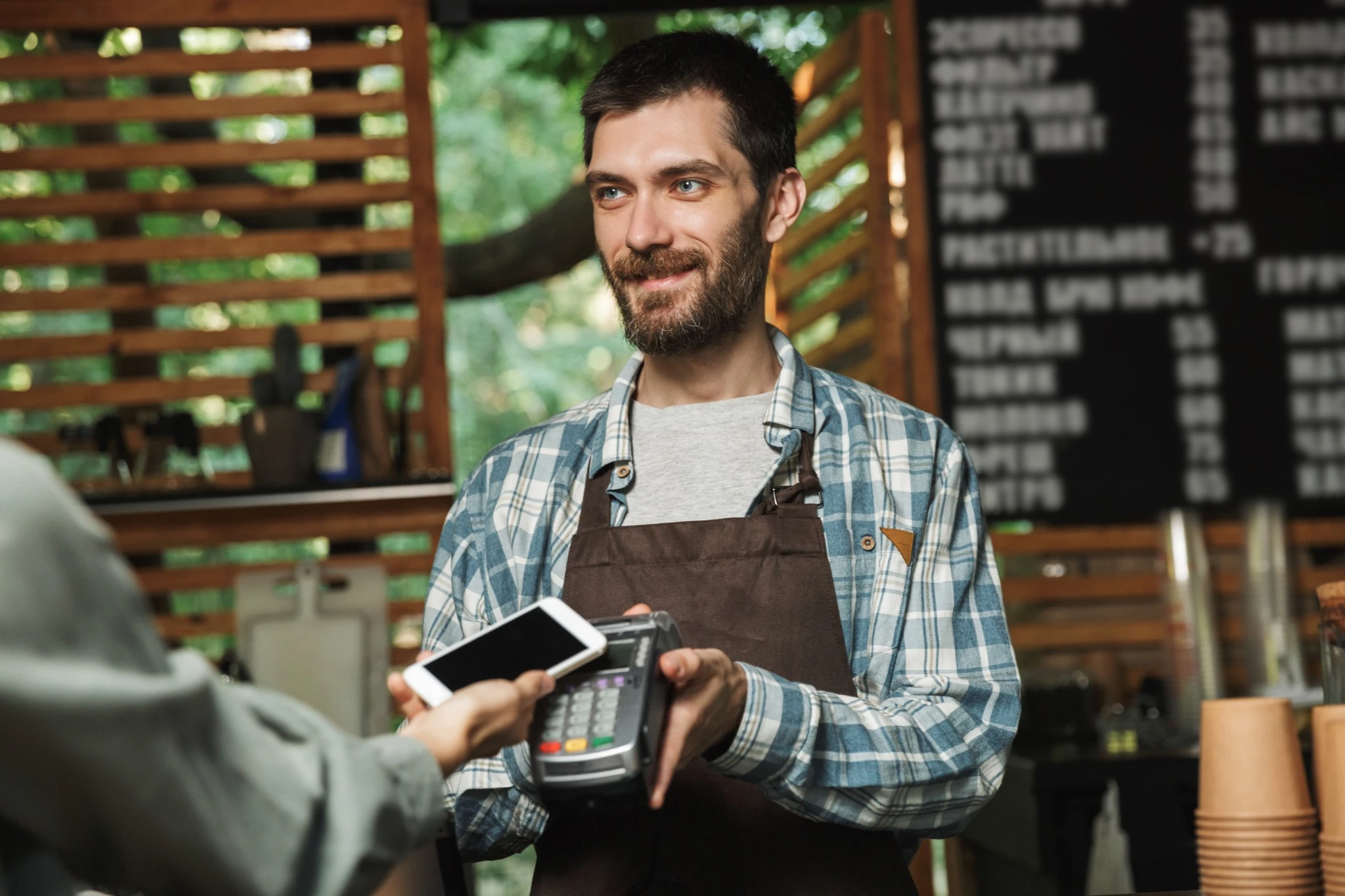 Cafe staff member processing a mobile payment with a POS terminal